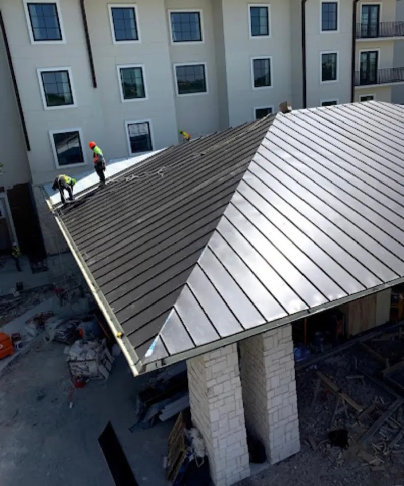 Crew installing standing seam metal roof panels on a commercial project in Gillette